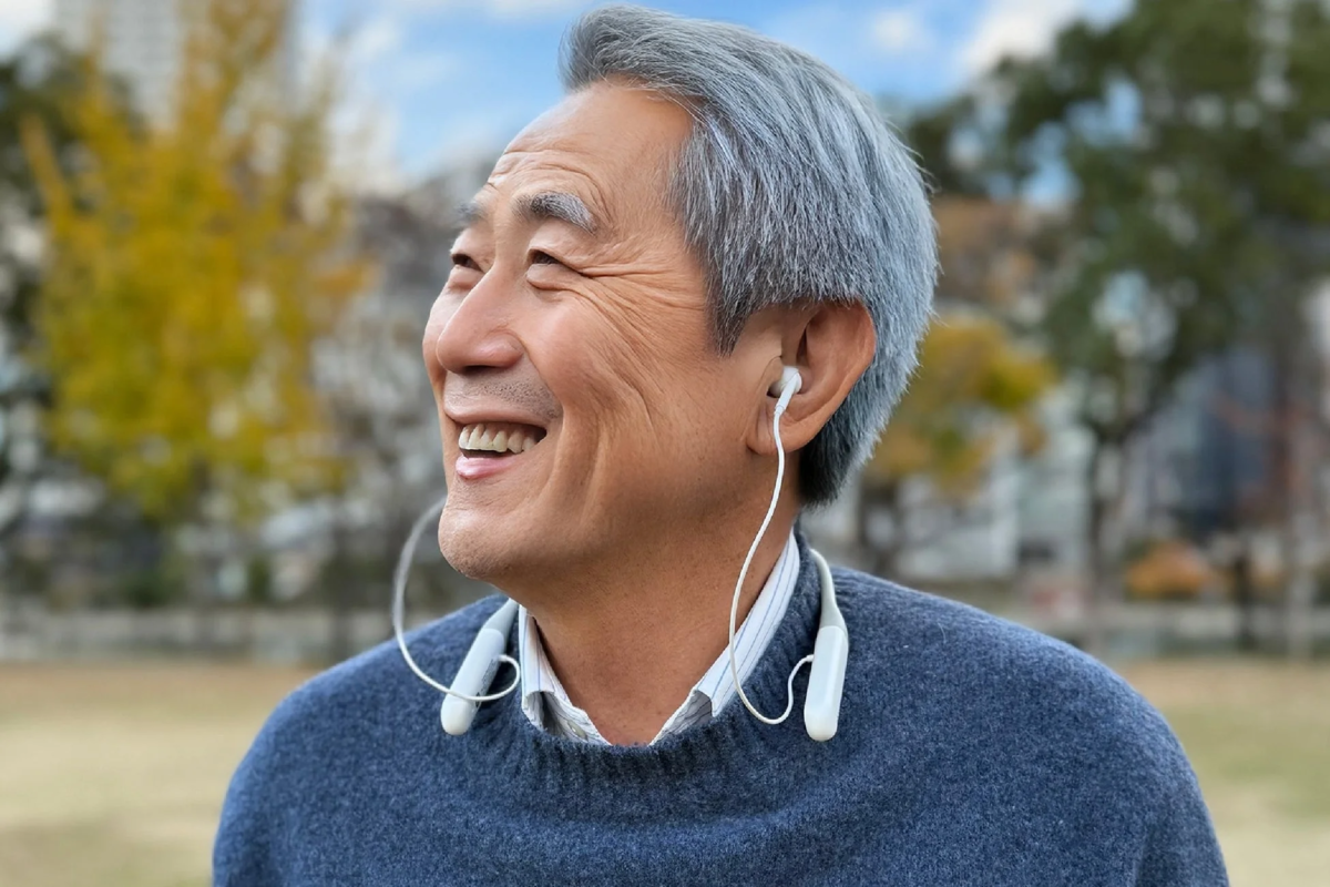Elderly man outdoors wearing neckband device