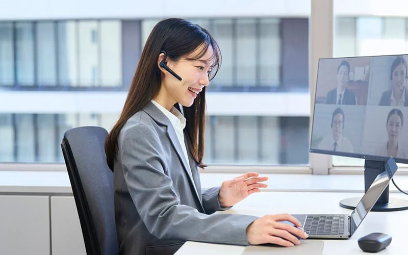 Smiling woman in an office participating in a video conference with a headset