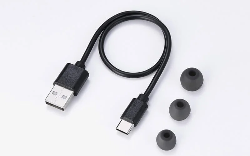USB-A to USB Type-C charging cable and three sizes of grey ear caps on a white background