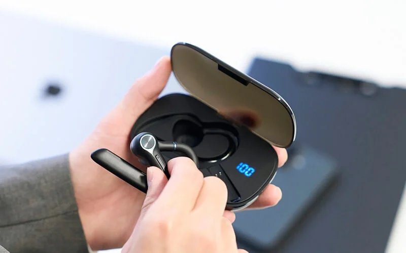 Wireless earphone being removed from a charging case, with '100' displayed digitally on the case