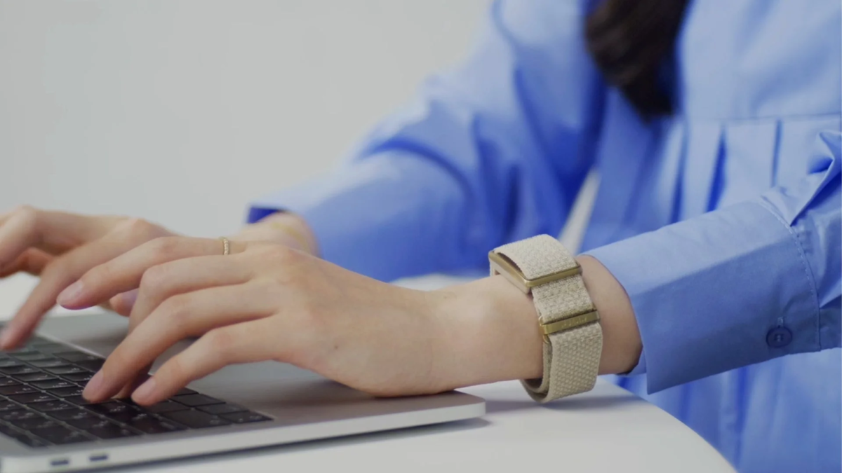 Person typing on a laptop with POLAR Loop on wrist