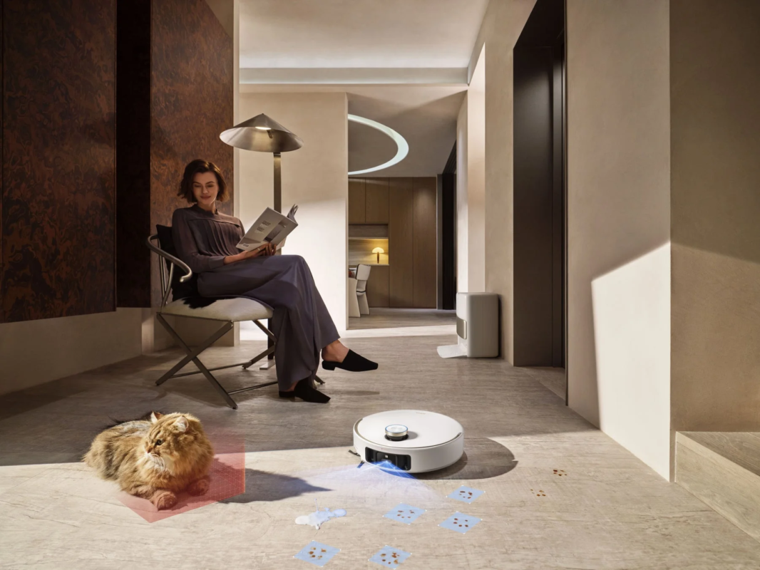 Woman reading, cat, robot vacuum cleaning