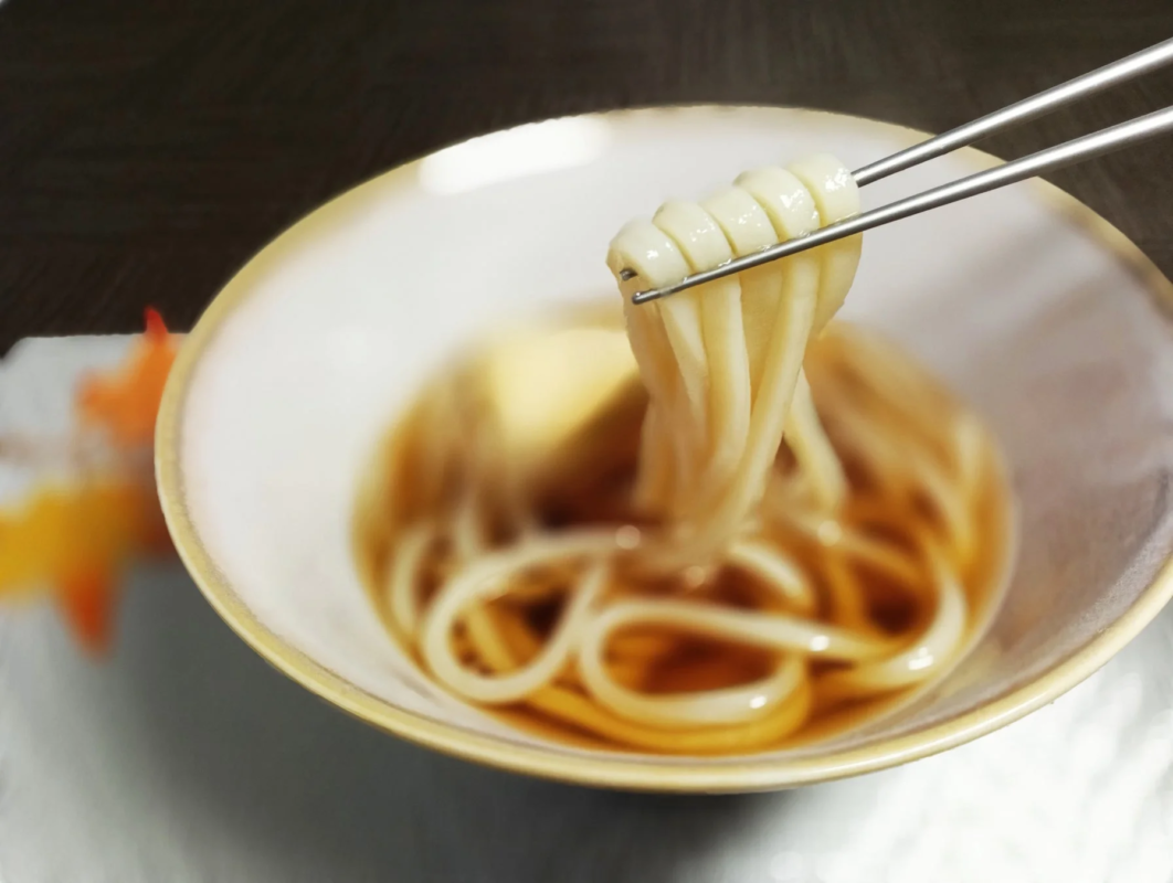 Udon noodles being picked up with chopsticks