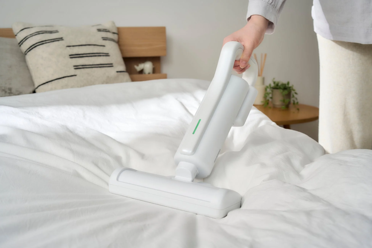 Lightweight futon cleaner in use on a bed