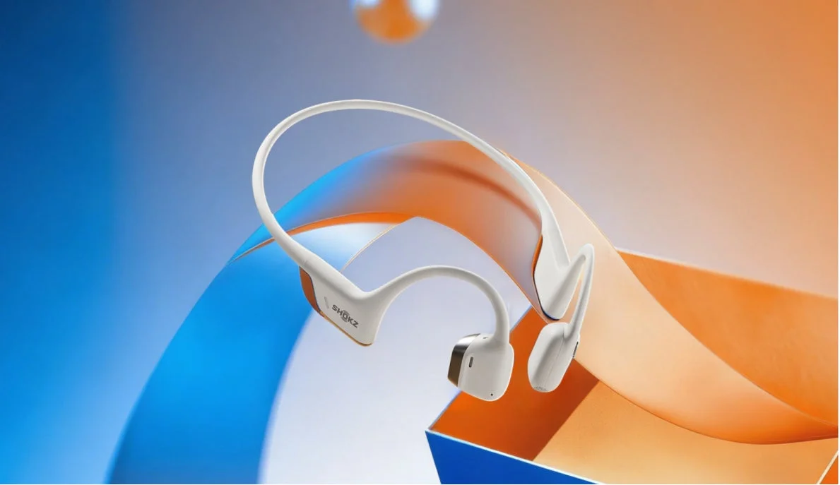 White bone conduction headphones on a blue and orange gradient background