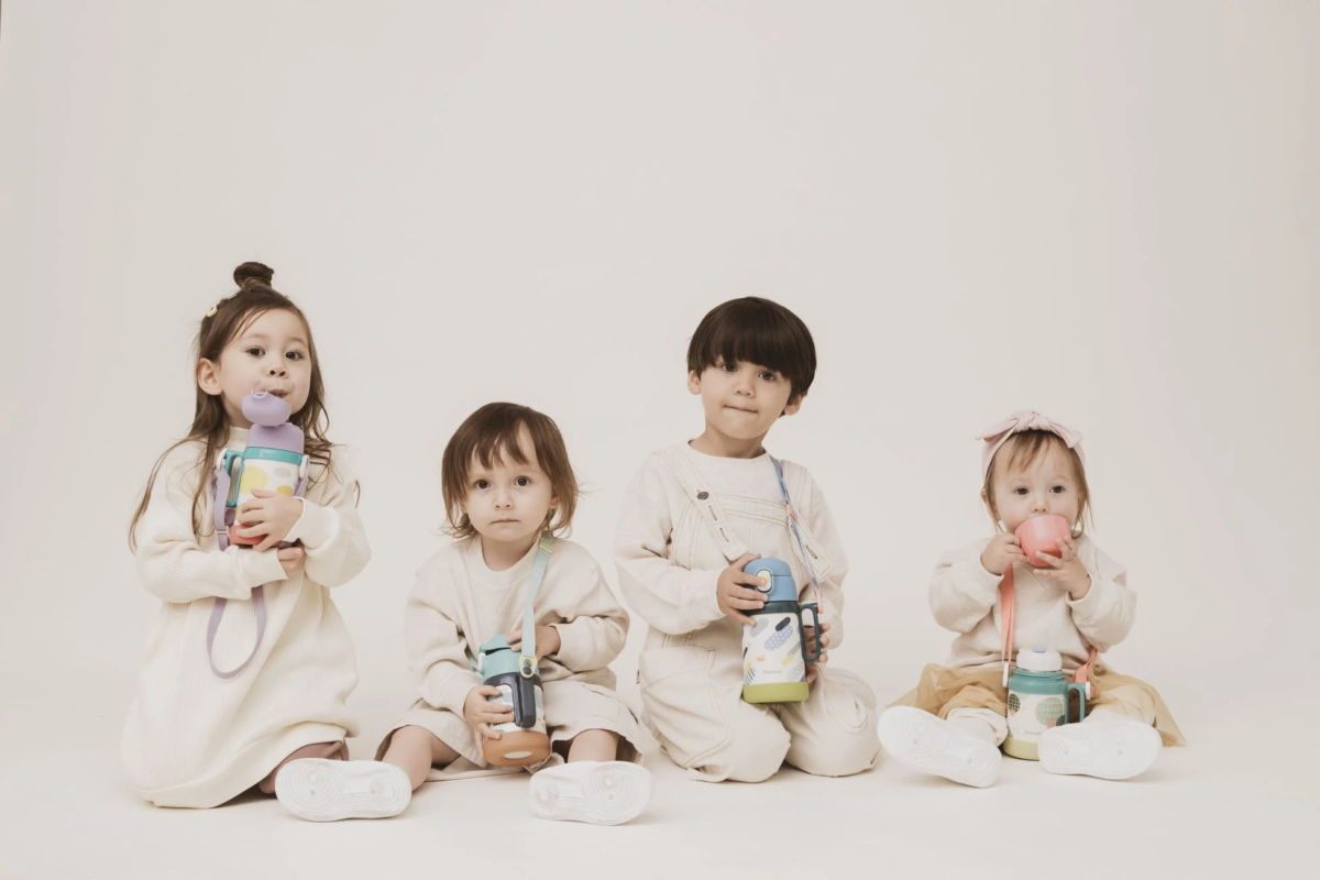 Four young children holding colorful water bottles and cups