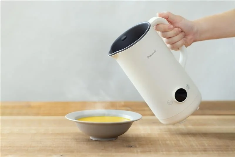 White electric kettle pouring a yellow liquid into a bowl