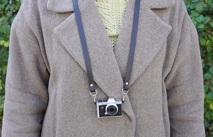 Person wearing a coat with the mini camera around their neck