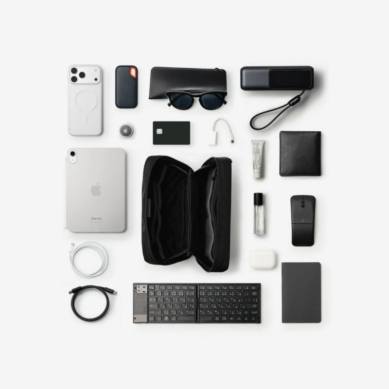 A flat lay of various digital gadgets and personal items, including an iPad mini, organized on a white background