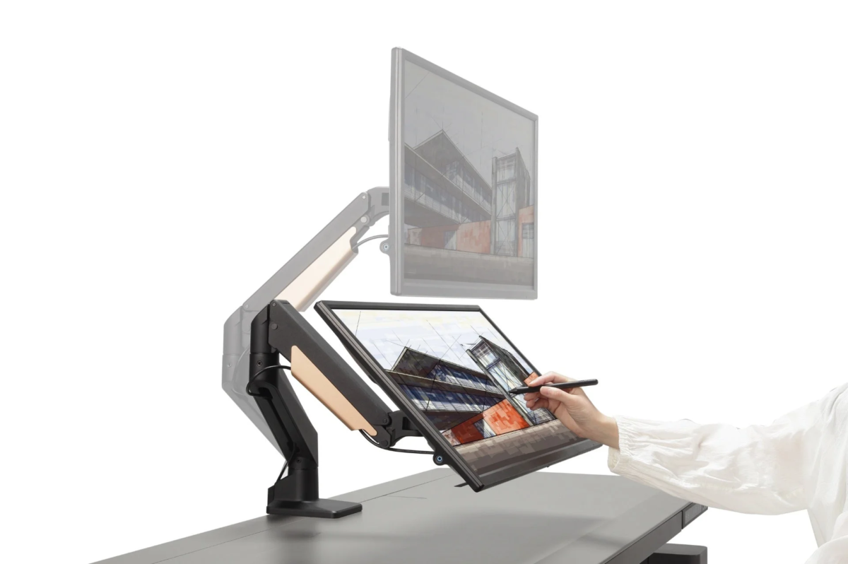 Person using a stylus on a drawing tablet mounted on a monitor arm