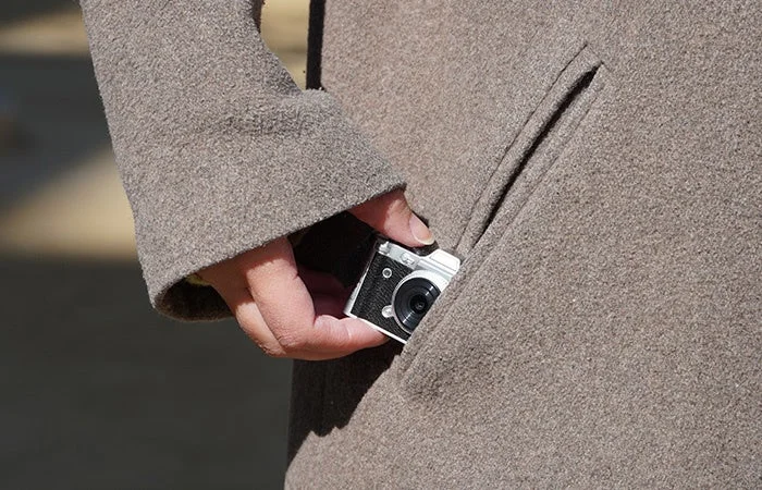 Mini camera being put into a coat pocket