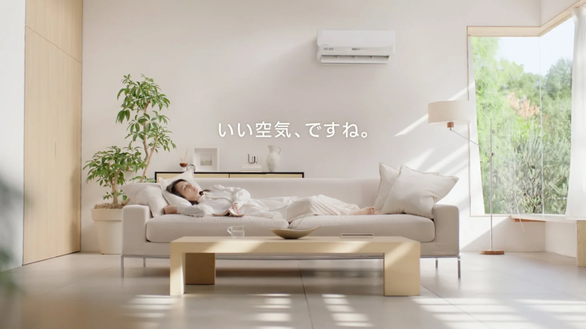 Keiko Kitagawa napping on a sofa in a bright living room with an air conditioner visible