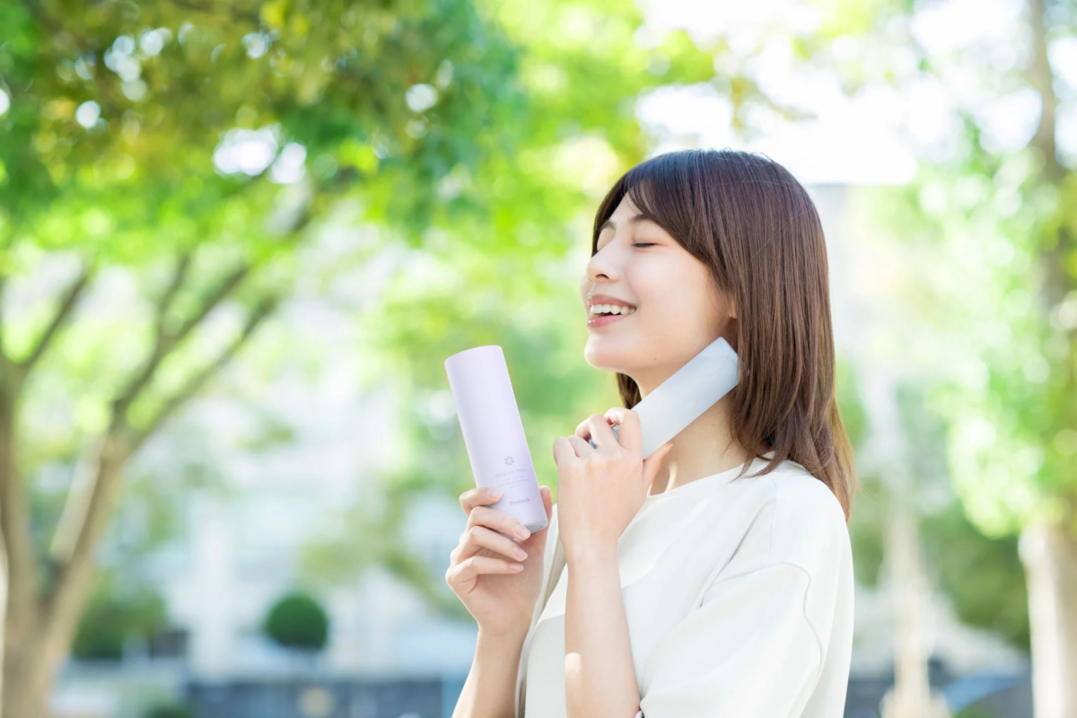Smiling young woman using a cooling product outdoors