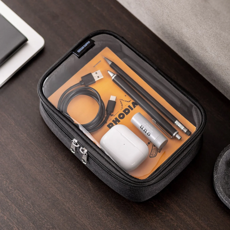 Transparent pouch containing stationery, earbuds, and lip balm