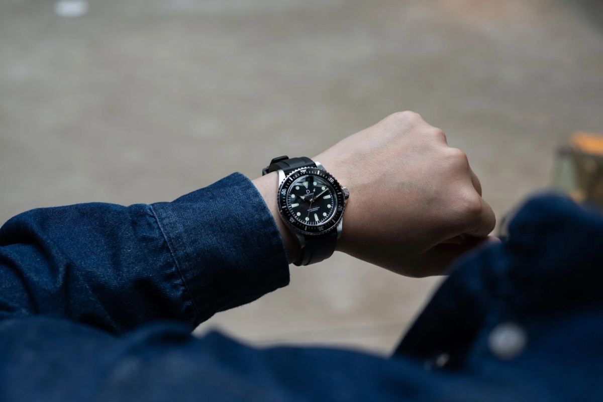 Close-up of a person wearing a diver's watch with a black dial and rubber strap