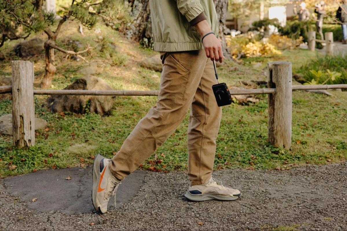 Person walking on a gravel path with a compact camera