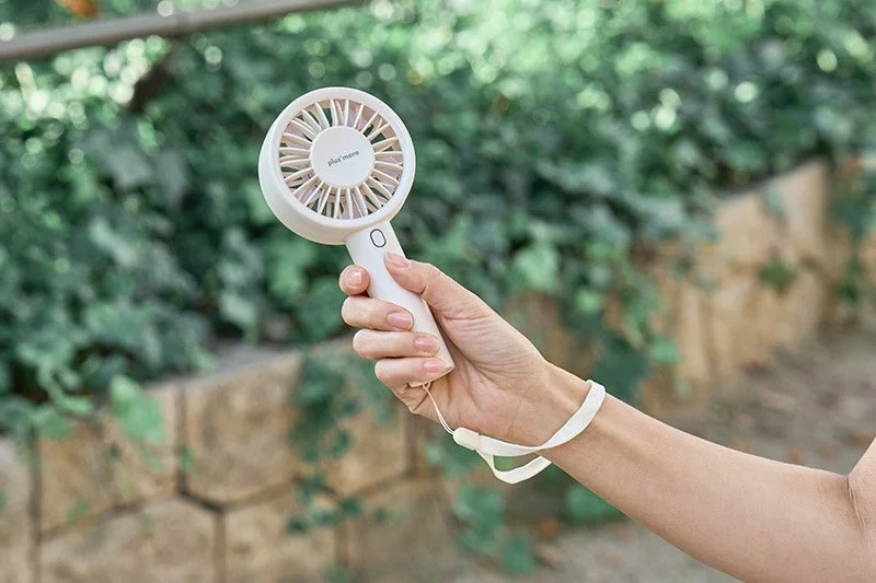 Hand holding a white handy fan outdoors