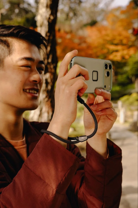 Man photographing with a smartphone on a wrist strap