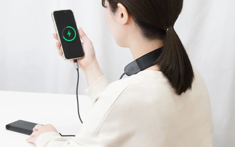 A person charging their smartphone using the shoulder cable, highlighting the charging functionality.