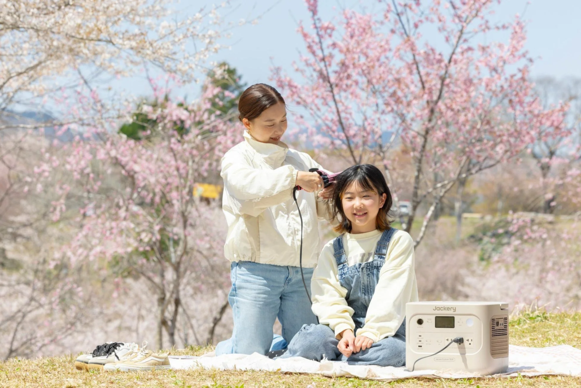 Family using Jackery power station for hair styling outdoors