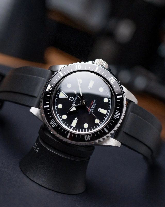 Close-up of a vintage-style diver's watch with a black dial and rubber strap on a display stand