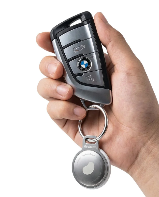 Hand holding a BMW smart key with Tag.O attached