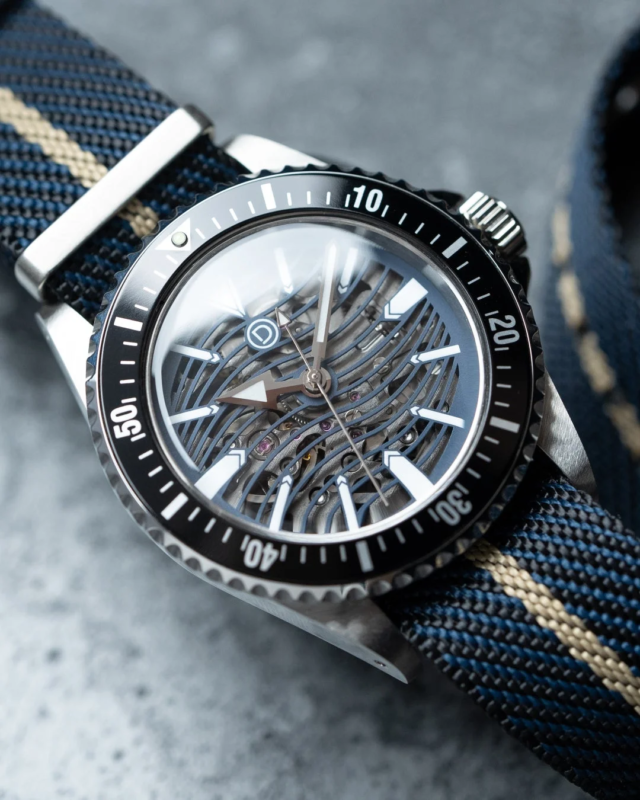 Close-up of a mechanical watch with a skeleton dial and a blue and beige NATO strap