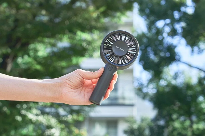Hand holding a black handy fan outdoors