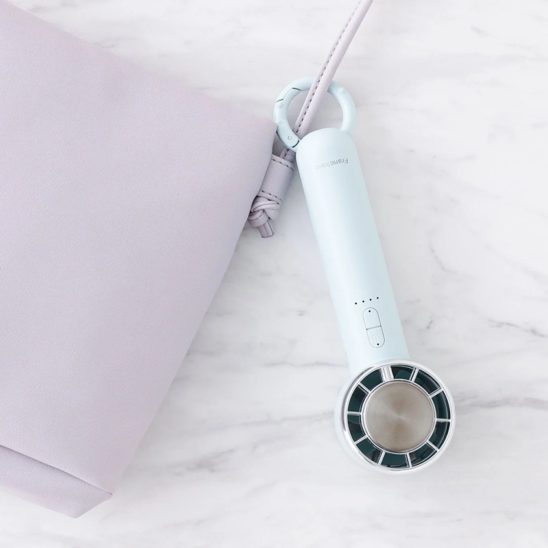 Light blue handy fan and purple bag on marble