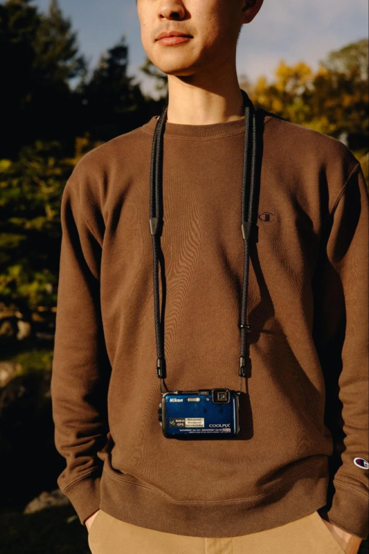 Man wearing a blue Nikon COOLPIX digital camera