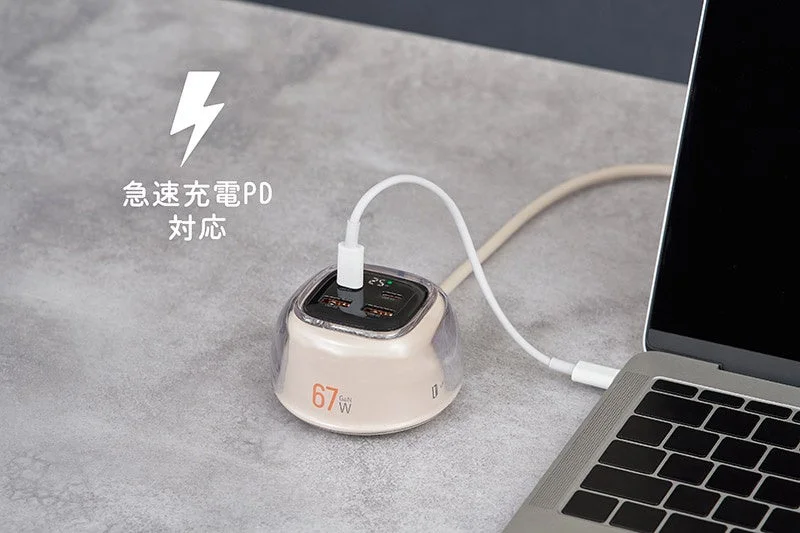 A 67W GaN rapid charger connected to a laptop on a desk, showing PD compatibility.