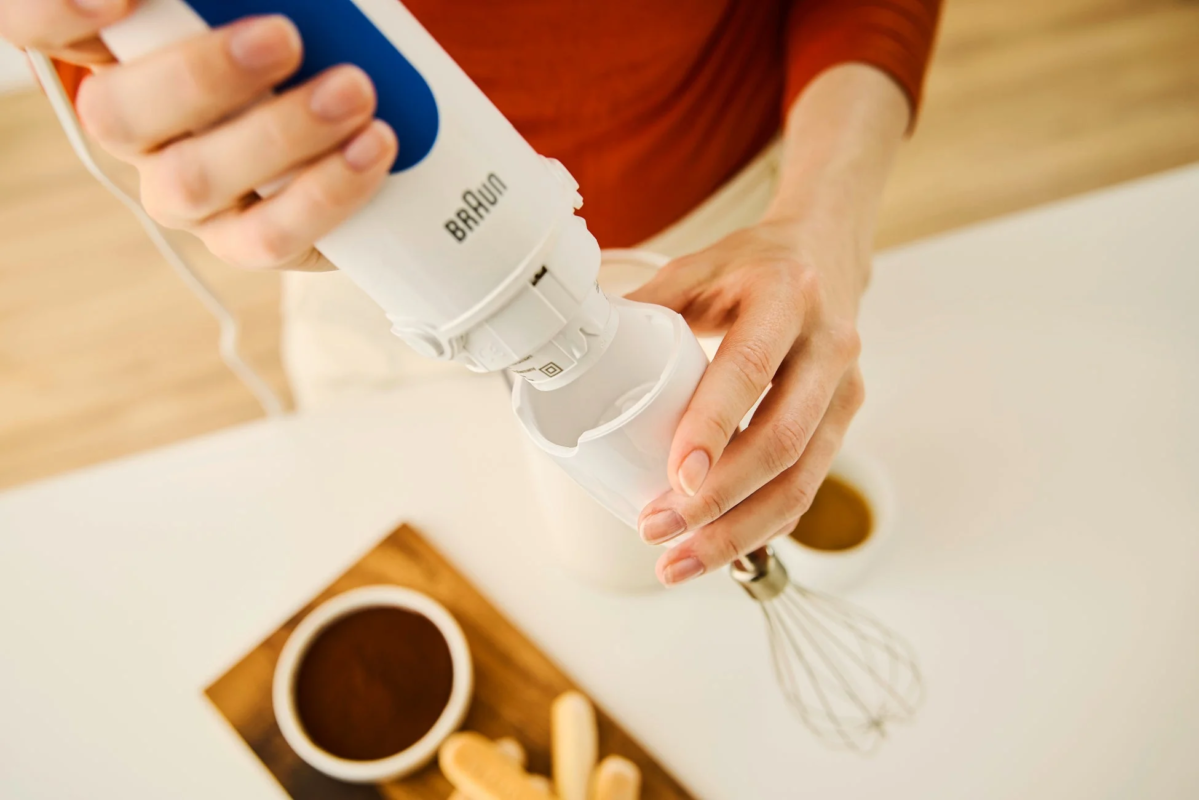 Woman preparing something with a Braun hand blender on a white table