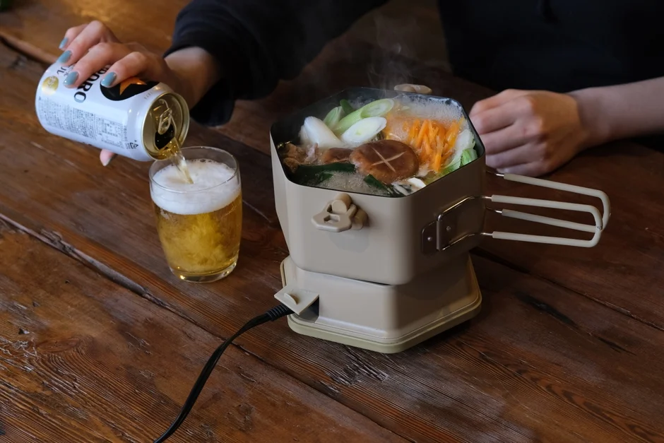 A hot pot dish being served with a glass of beer