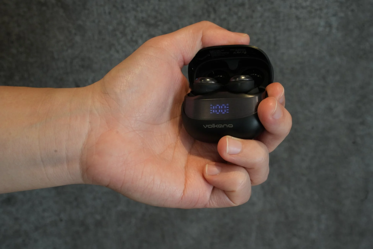 A hand holding the VK-ASPEN earphone charging case, showing '100%' battery life.