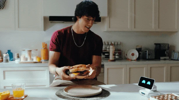 Man with a hamburger and LOOI in the kitchen
