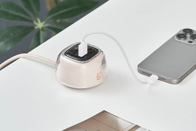 A smartphone charging via a USB charger on a white table, showing a '67' display.