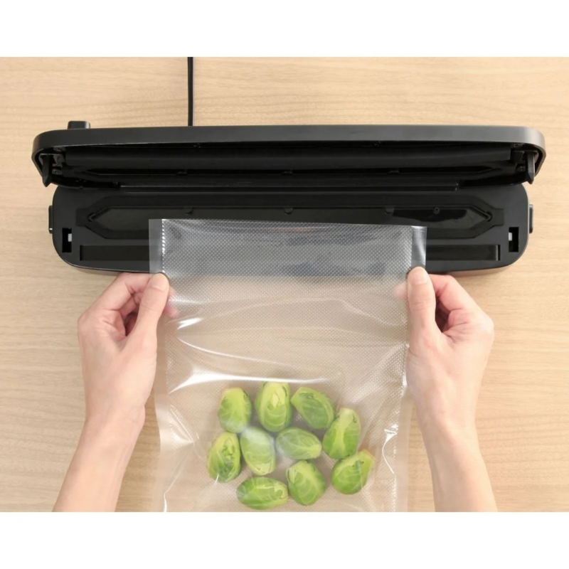 Hands placing vegetables into sealer