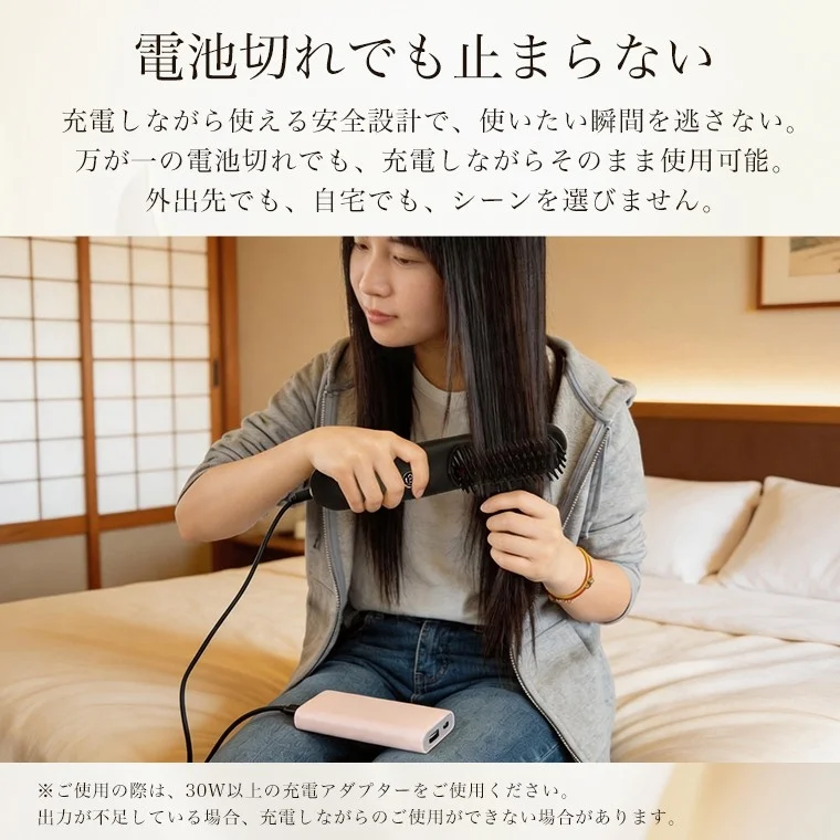 A woman sitting on a bed, using a hair brush styler while it is charging, highlighting its convenience.