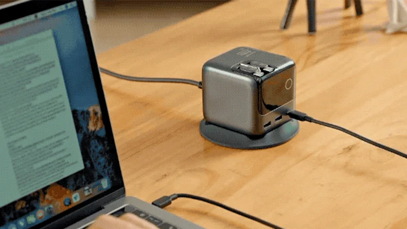 Laptop connected to a power adapter on a wooden desk