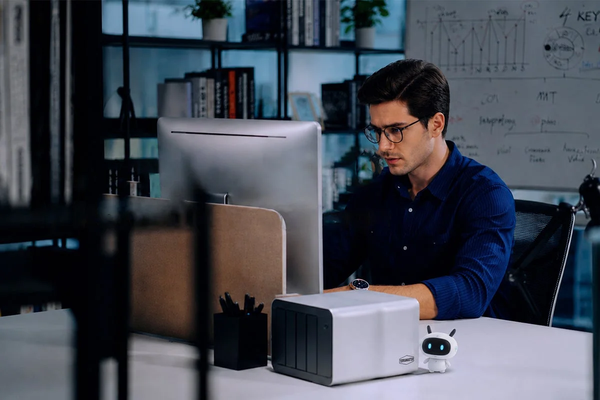 Man working at a desk with a NAS device and a small robot