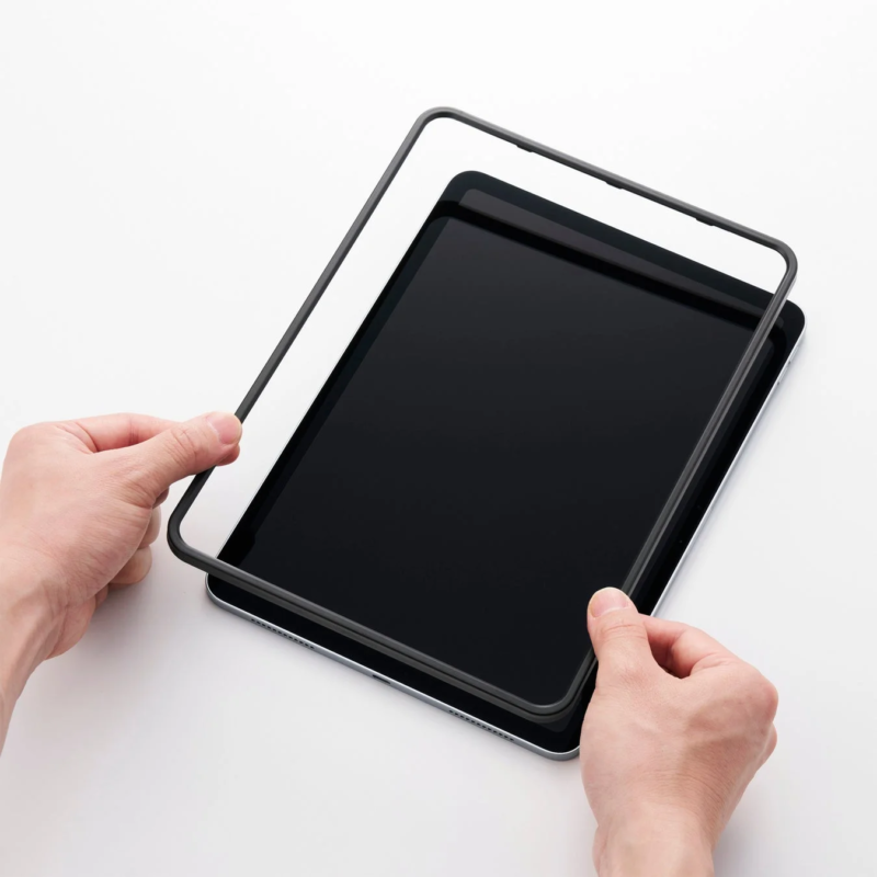 Hand applying a screen protector to a tablet