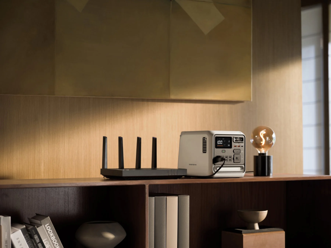 Router, portable power station, and lamp on a wooden shelf