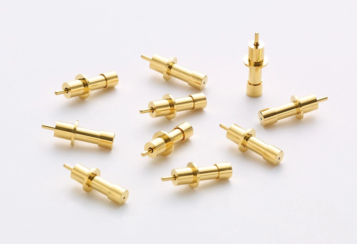 Multiple small golden cylindrical metal parts, precision electronic components or connectors, white background