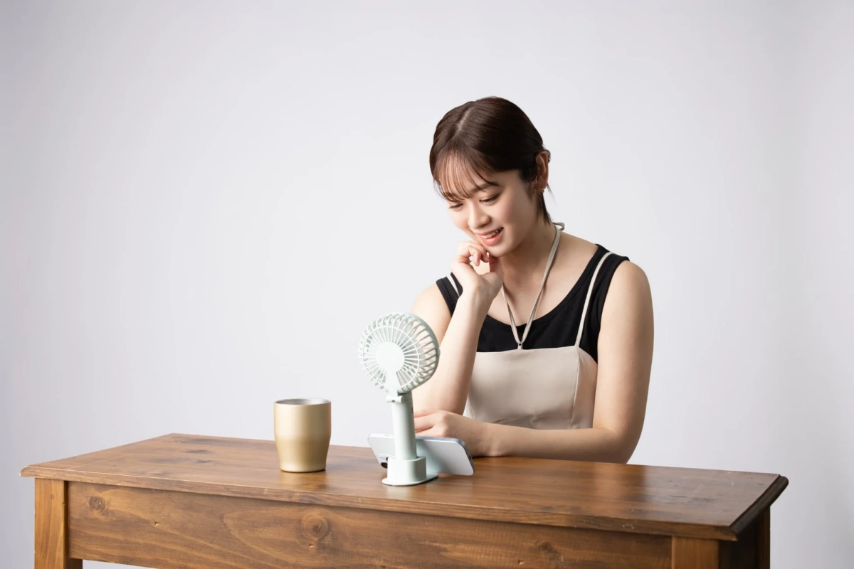 Woman using tabletop fan with smartphone