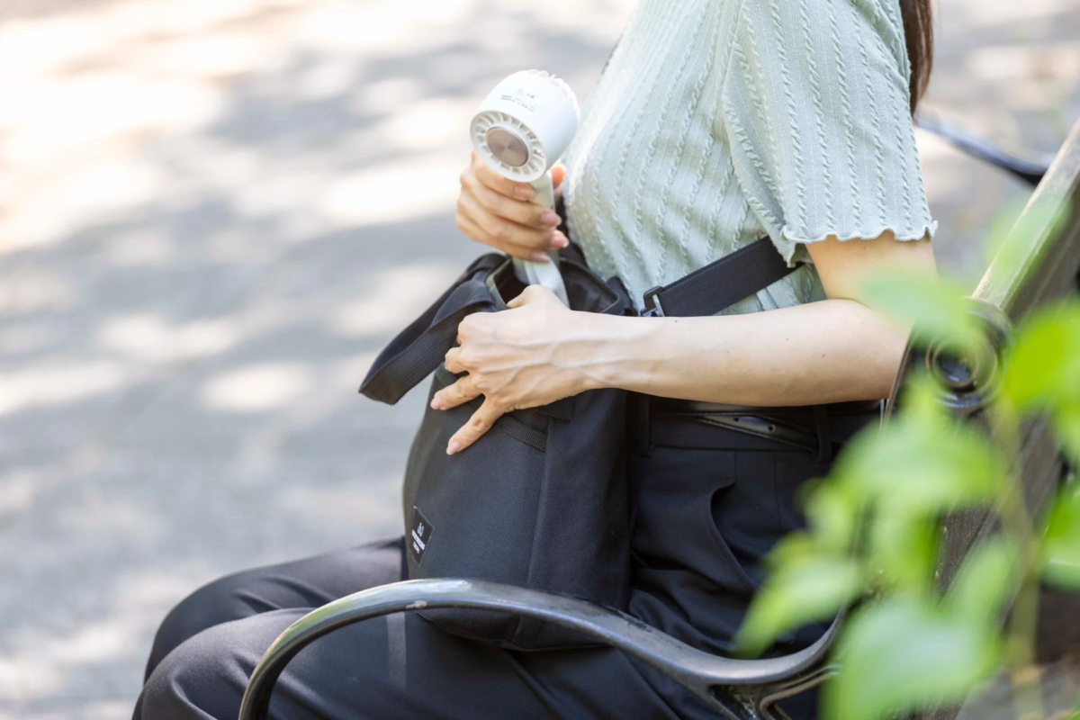 Woman putting fan into BATTERY SHIELD BAG