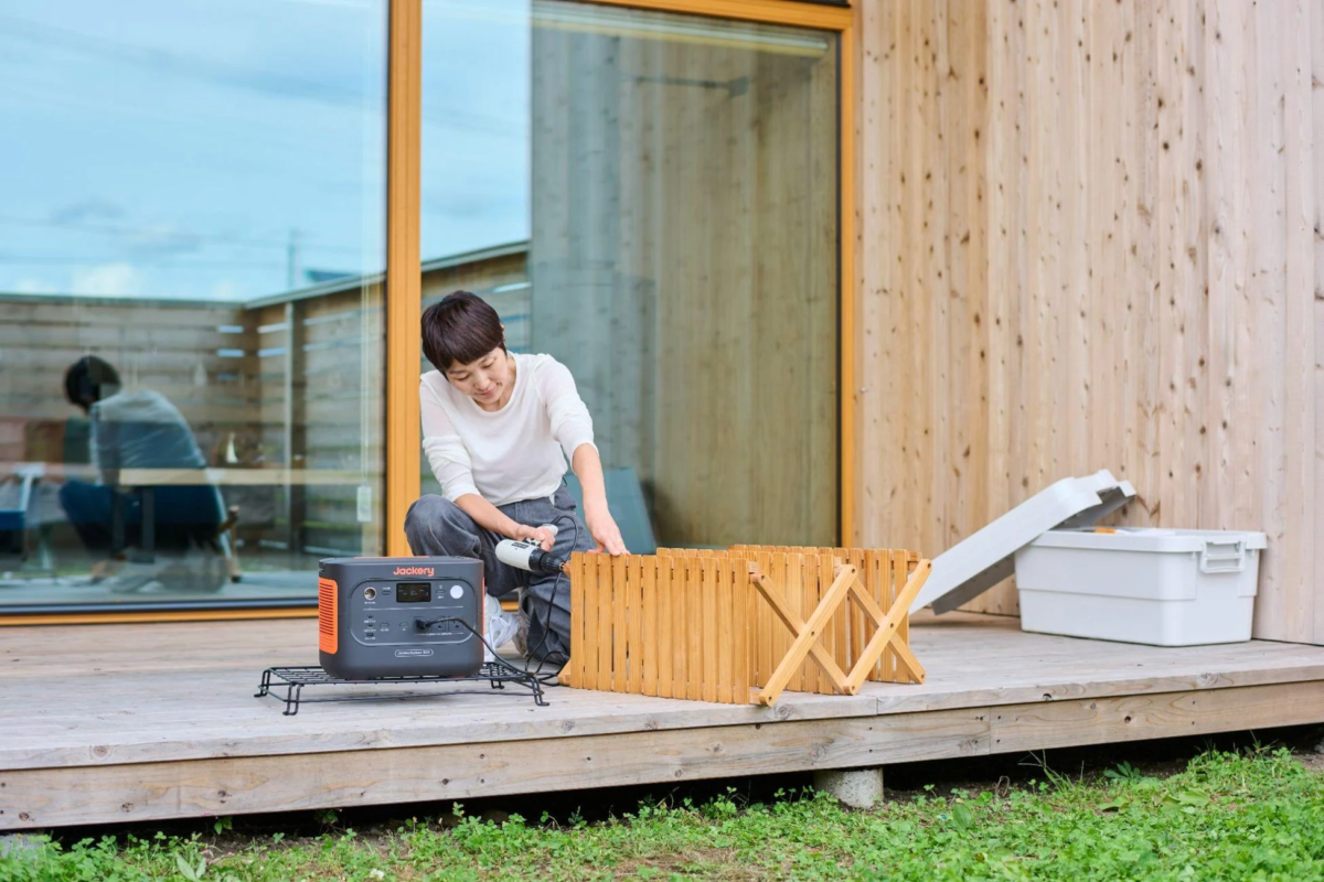 Woman using Jackery Portable Power Station 1500 New outdoors on a deck