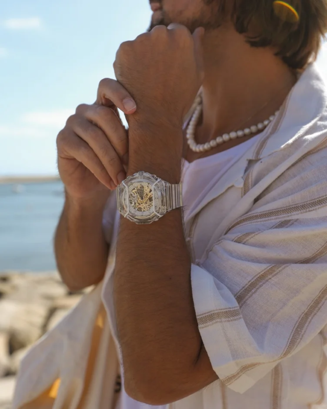 Man wearing a transparent skeleton watch with a pearl necklace