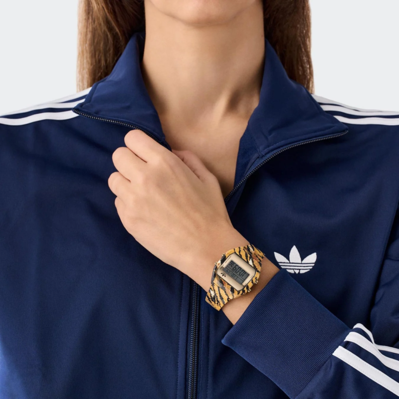 Close-up of a person wearing a tiger print adidas Digital Two watch with an adidas tracksuit