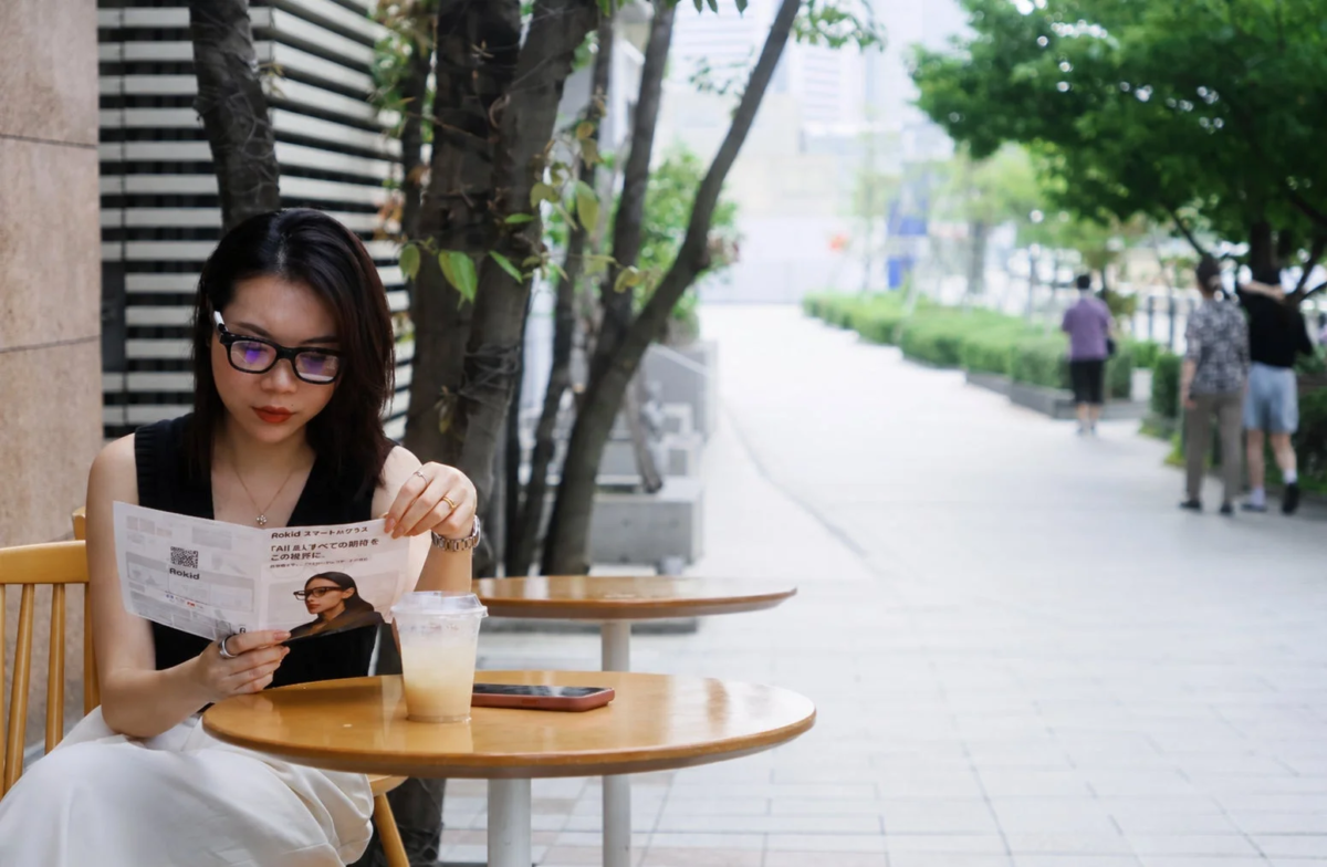Woman reading Rokid brochure at outdoor cafe