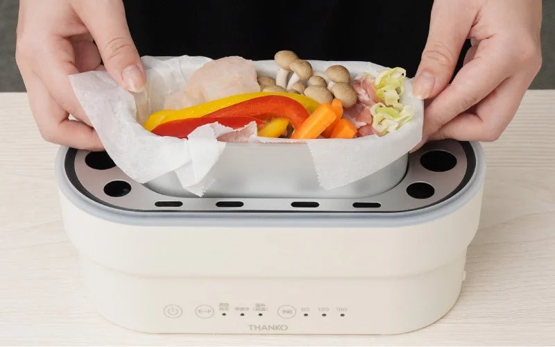 Setting up a compact electric cooker with colorful vegetables and meat